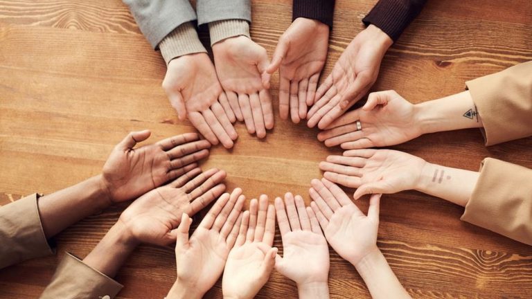 Hands reaching together in a circle on a wooden table