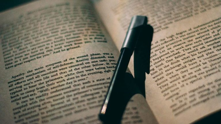 An open book with a pen resting on the page