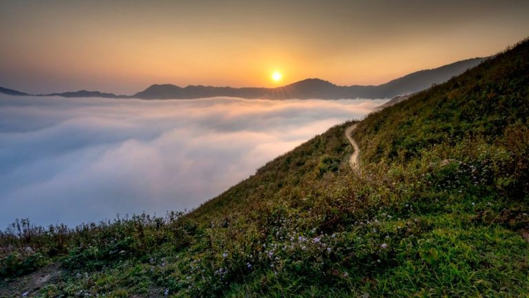 Sunrise over clouds above a mountain path